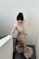 A woman wearing the Vogsion Bias Maxi Dress in Rose Garden Revolution, a pink and beige floral print dress with a ruffled mermaid hem and V-neckline, showcased by a real Vogsion customer