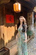 Woman in a long dress standing in front of a wooden building with lanterns and signs.