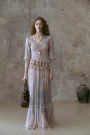 Woman in Vogsion Tiered Pleated Lace-Trimmed Printed Silk Maxi Skirt standing against a textured wall.