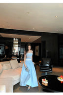Woman in a light blue dress standing in a modern living room.