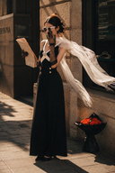 Model reading a newspaper in the Vogsion Éternelle contrast brooch maxi dress, featuring built-in padded cups, gold-tone waist buttons and a floor-length black skirt.