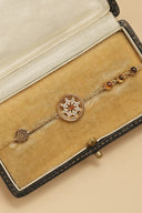 Gold bracelet with decorative elements on a beige velvet jewelry box
