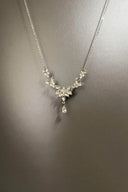 Silver necklace with floral design on a gray background