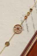 Delicate gold bracelet with gemstones on a textured surface