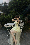 Woman in a Vogsion Pistachio Green Strapless Corset Ruffle Peplum Lace Prom Dress 2026 sitting on a metal chair outdoors.