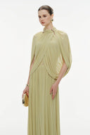 Woman wearing Vogsion Light Pomelo Olive Mesh Knit Draped Cape Pleated Maxi Dress with a draped design on a white background