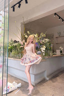 Woman in a floral dress standing in front of a flower shop window.