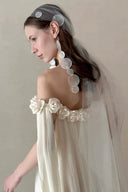 Vogsion Romantic Off-Shoulder Pleated Maxi Dress Ivory Rose Border 2026 – flowy boho summer maxi dress with rose appliqué, pleated layers, cape veil overlay, and ethereal movement in neutral gallery setting