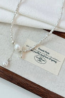 Vogsion Céleste Pearl Lariat Necklace on a wooden tray with a white cloth background