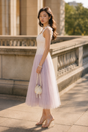     Vogsion Moonlit Lavender Petal lined tulle midi dress with ivory textured bodice, ruffle straps, and pearl bag in outdoor side view
