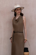 Woman wearing a brown dress and white hat against a beige background