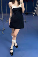 Person wearing Vogsion Antoinette Structured Bow Tailored Mini Dress and white stockings on a blue floor.
