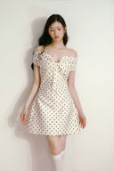 Model wearing Vogsion off-shoulder ivory and black polka dress under soft natural light, elegant and timeless look