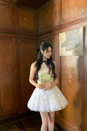 Woman in a Vogsion Shush Trong Renaissance Stiff Wool-Lace Coquette Dress holding a green book in a room with wooden paneling.