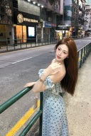 Woman in a polka dot dress standing on a street with buildings in the background