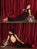 Woman in a  Vogsion Midnight Lotus Qipao-Inspired Backless Black Evening Gown posing on a stage with red curtains and disco balls.