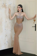 Woman in a Vogsion Sparkly Crystal Rhinestone Nude Mermaid Halter Prom Dress standing in a room with decorative wallpaper.