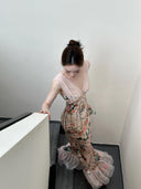 A woman wearing the Vogsion Bias Maxi Dress in Rose Garden Revolution, a pink and beige floral print dress with a ruffled mermaid hem and V-neckline, showcased by a real Vogsion customer