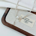 Vogsion Céleste Pearl Lariat Necklace on a wooden tray with a white cloth background