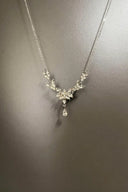 Silver necklace with a floral pendant on a gray background