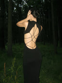 Person wearing Vogsion Midnight Lotus Qipao-Inspired Backless Black Evening Gown with open back in a forest setting