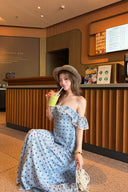 Woman in a polka dot blue dress holding a drink in a casual setting