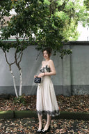 Woman in Vogsion "Lucienne" Ethereal Tulle & Contrast Lace-Inset Midi Dress standing outdoors with greenery and a wall in the background