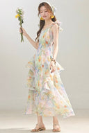 Woman wearing Vogsion Watercolor Cascade tiered ruffle dress dress holding flowers against a plain background