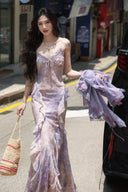 A customer wearing the Vogsion Evangeline floral maxi dress with a woven straw bag and gold jewelr