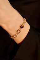 Gold bracelet on a wrist against a dark background