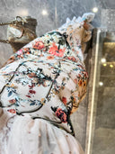 A woman wearing the Vogsion Bias Maxi Dress in Rose Garden Revolution, a pink and beige floral print dress with a ruffled mermaid hem and V-neckline, showcased by a real Vogsion customer
