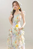 Woman wearing a Vogsion Watercolor Cascade tiered ruffle dress holding flowers against a plain background