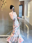 A woman wearing the Vogsion Bias Maxi Dress in Rose Garden Revolution, a pink and beige floral print dress with a ruffled mermaid hem and V-neckline, showcased by a real Vogsion customer