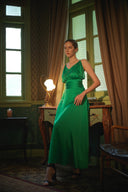 Woman in a green dress standing in a room with large windows and vintage decor.