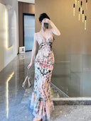 A woman wearing the Vogsion Bias Maxi Dress in Rose Garden Revolution, a pink and beige floral print dress with a ruffled mermaid hem and V-neckline, showcased by a real Vogsion customer