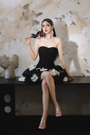 Woman in a Vogsion Midnight Bloom Architectural Mini Dress with floral details sitting on a ledge against a textured wall.