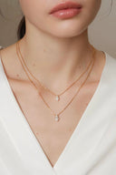     Vogsion Minuit Éclat gold pendant necklace with D color oval moissanite stone styled with white outfit for minimalist luxury look.