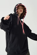 Person wearing a black hoodie with pink drawstrings on a white background