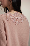 Back view of Vogsion soft pink knit cardigan showing intricate floral lace appliqué across shoulders and upper back, delicate scalloped edges, cozy lace detail knitwear on real customer photo