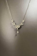 Silver necklace with floral pendant on a gray background