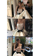 Woman wearing a Vogsion Élodie Lace Corset Bow Satin Maxi Dress with a black bow in a room.