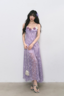 Woman wearing a purple floral dress against a white background