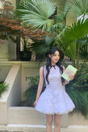 Woman in a Vogsion Shush Trong Renaissance Stiff Wool-Lace Coquette Dress holding a book in front of green plants