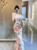 A woman wearing the Vogsion Bias Maxi Dress in Rose Garden Revolution, a pink and beige floral print dress with a ruffled mermaid hem and V-neckline, showcased by a real Vogsion customer