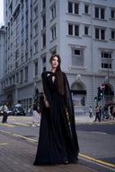 Vogsion Open Back Ribbon Maxi Dress – Elegant black pleated chiffon halter neck evening gown with dramatic sheer ribbon cape sleeves, open back cutouts, and flowing maxi skirt, worn by real Vogsion customer (not professional model) in luxury setting with global fast shipping