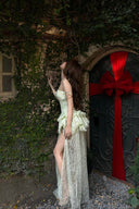 Woman in a Vogsion Pistachio Green Strapless Corset Ruffle Peplum Lace Prom Dress 2026 standing next to a door with a red ribbon, surrounded by ivy.