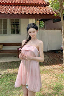 Woman in a Vogsion Odette Pearl-Trim Bubble Mini standing outdoors near a house with a tiled roof.