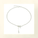 Vogsion Céleste Pearl Lariat Necklace with a pearl pendant on a light beige background