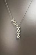 Silver necklace with floral pendant on a gray background