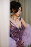 Woman in a Vogsion "Midnight Butterfly" Iridescent Sequin Backless Evening Gown with feathered sleeves against a neutral background